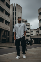 R3AKT Heather Grey Oversized Tee styled with black cargos — urban brutalist street editorial
